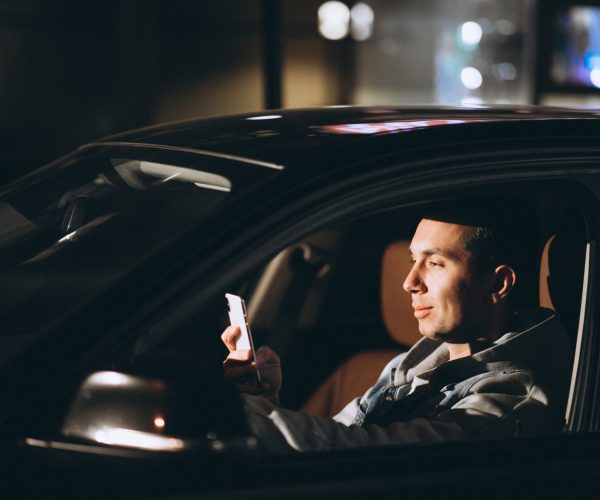 Young man driving his car at a night time and talking on the phone